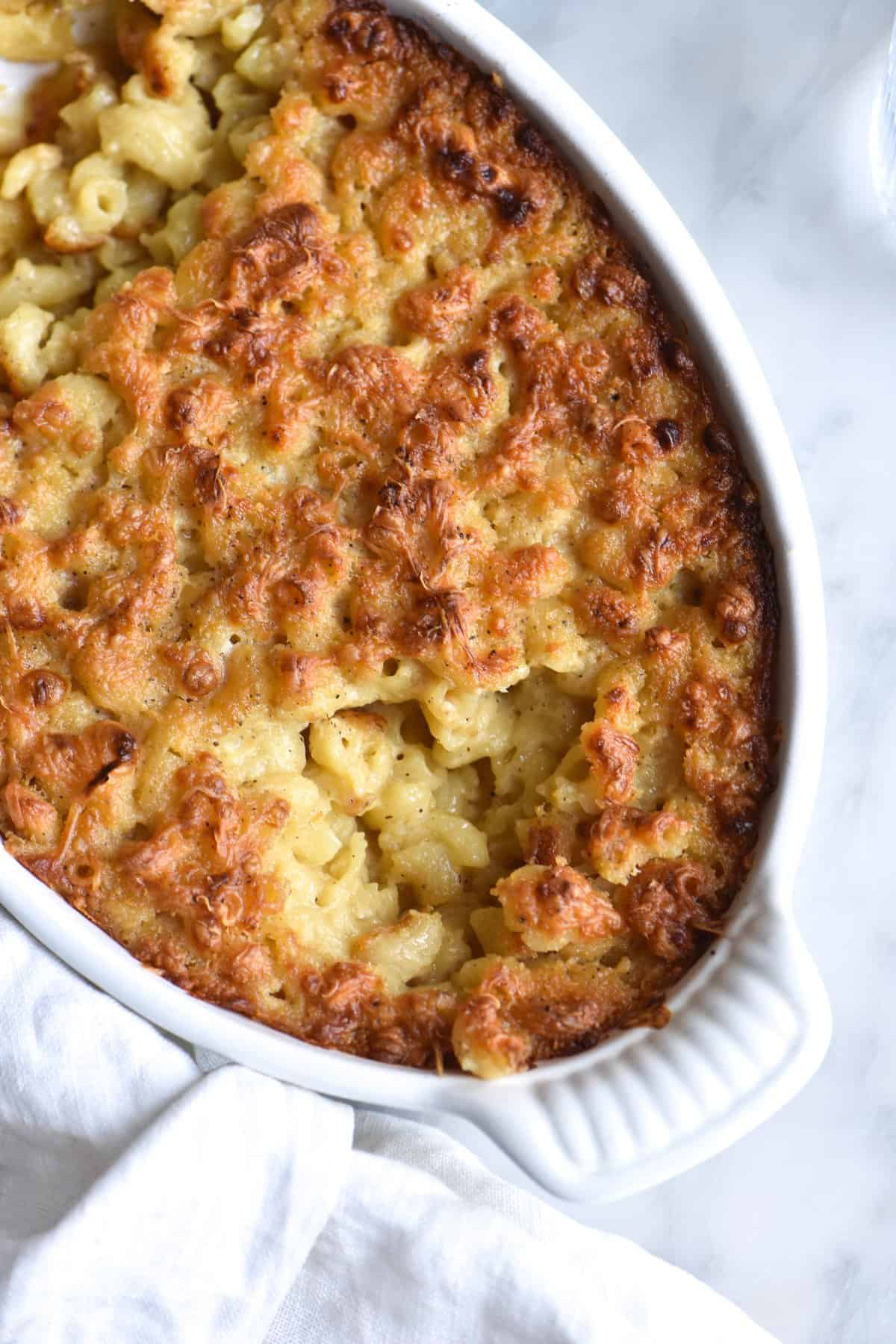 A close up of vegan gluten-free mac and cheese bake against a white marble backdrop