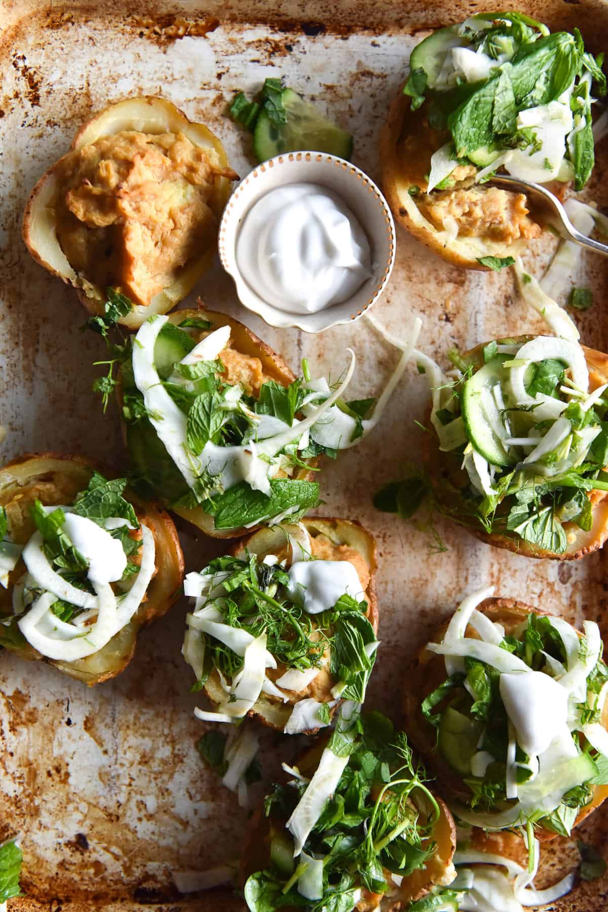 Vegan cheesy miso baked potatoes with fennel cucumber salsa on a rustic baking tray