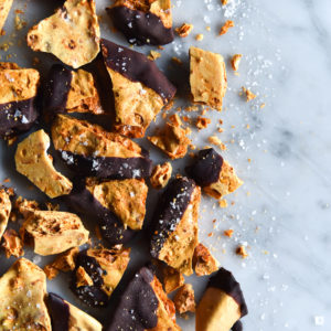 An aerial image of vegan chocolate dipped honeycomb shards on a white marble table