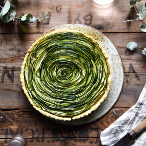 Grain free zucchini swirl tart on a wooden, moody backdrop