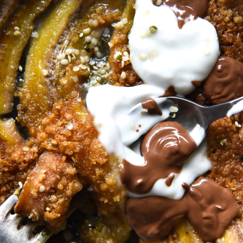 An aerial macro image of a gluten free breakfast crumble on bananas in a mini skillet.