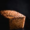 FODMAP friendly, gluten free nut loaf sits on a black baking tray against a black backrop