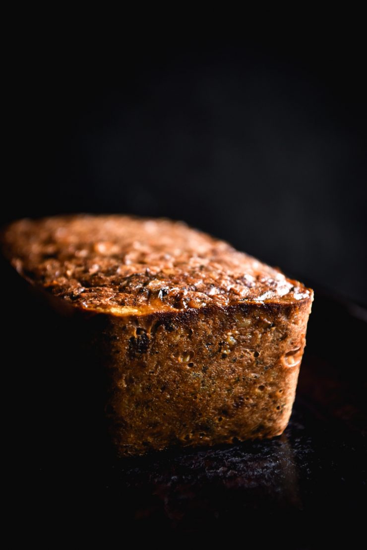 FODMAP friendly, gluten free nut loaf sits on a black baking tray against a black backrop