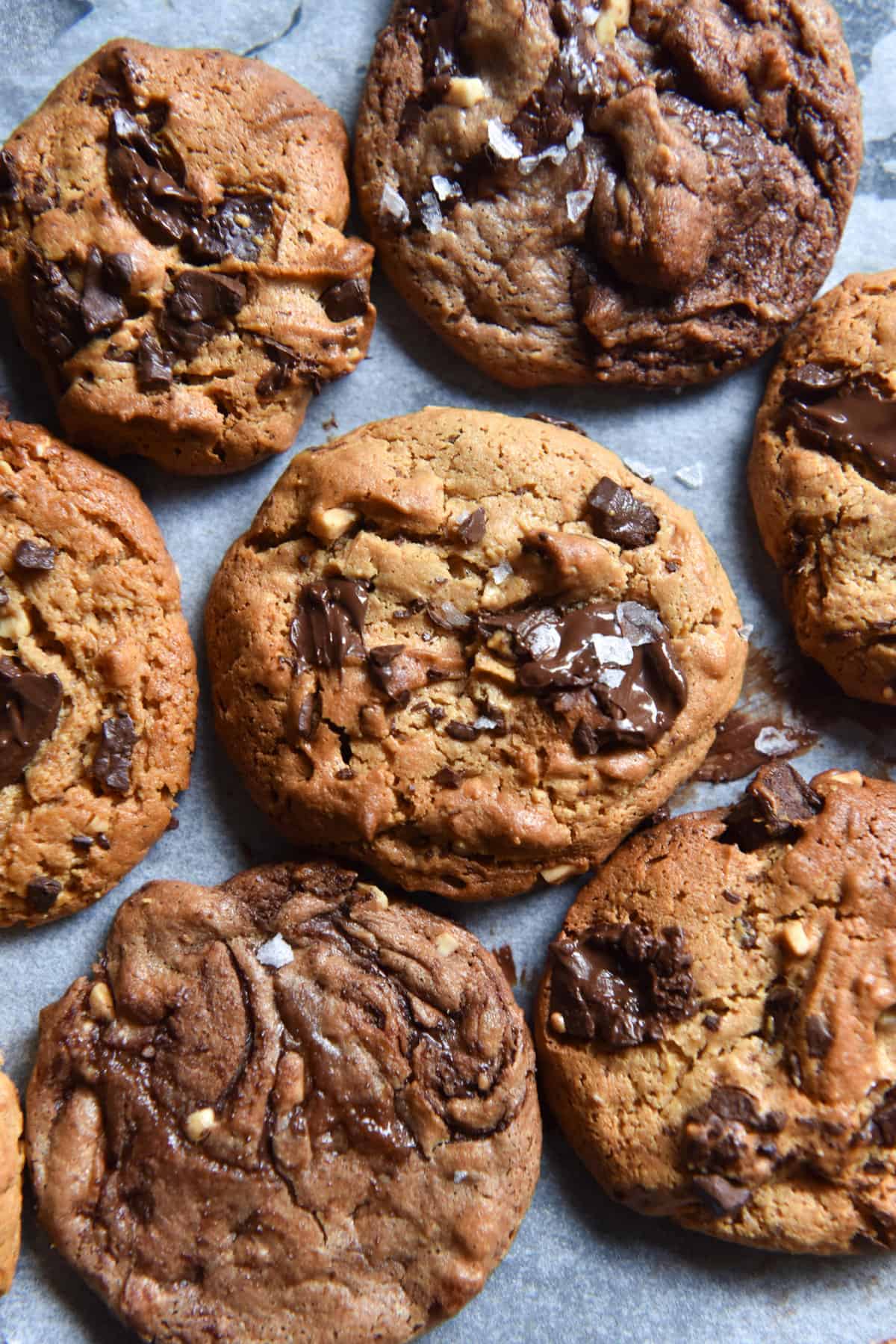 An aerial image of a tray of freshly baked peanut butter cookies studded with chocolate and topped with sea salt flakes.