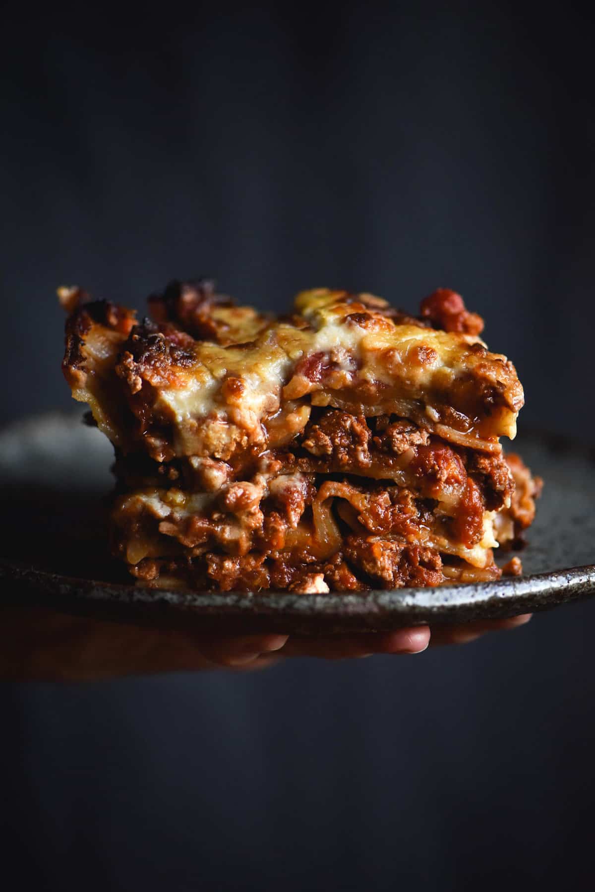 A side on view of a piece of vegan. gluten free and FODMAP friendly lasagne that uses vegan 'mince meat' and a vegan bechamel