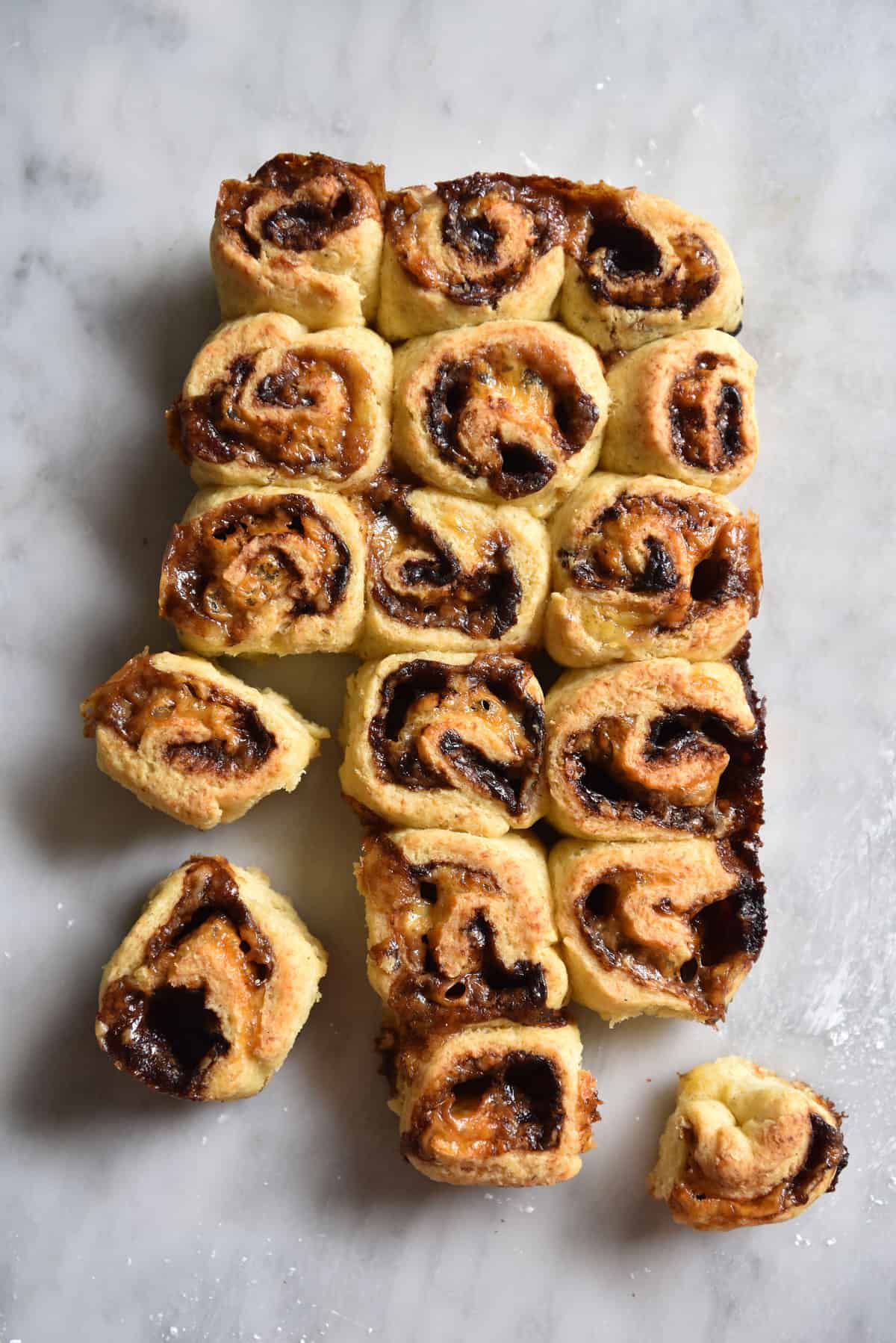 An aerial image of a group of gluten free Vegemite scrolls on a white marble table. 