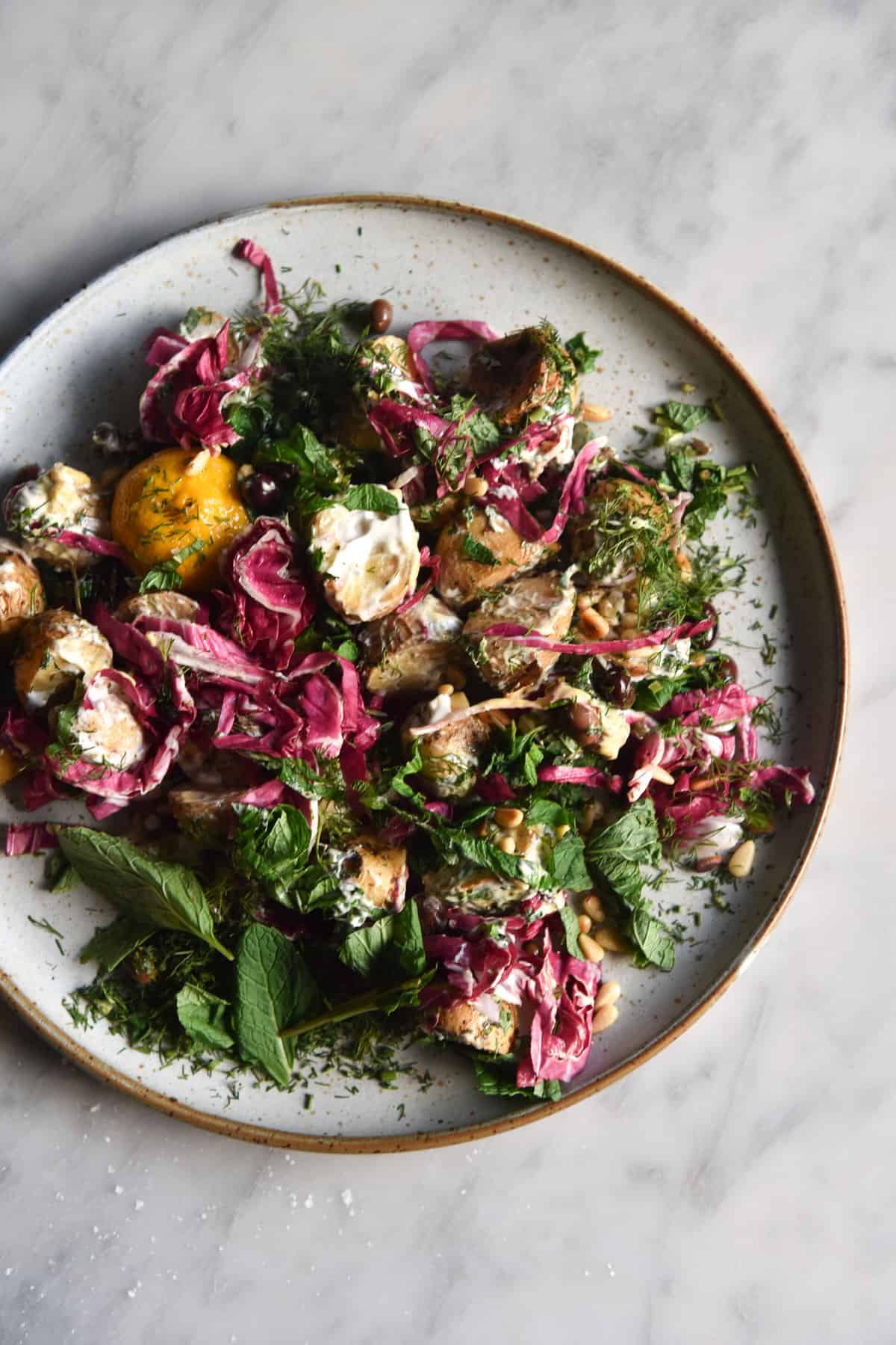 Vegan potato salad with a zingy mayo dressing, radicchio, olives, pine nuts and fresh herbs. FODMAP friendly, gluten free and easy to make. www.georgeats.com @georgeats