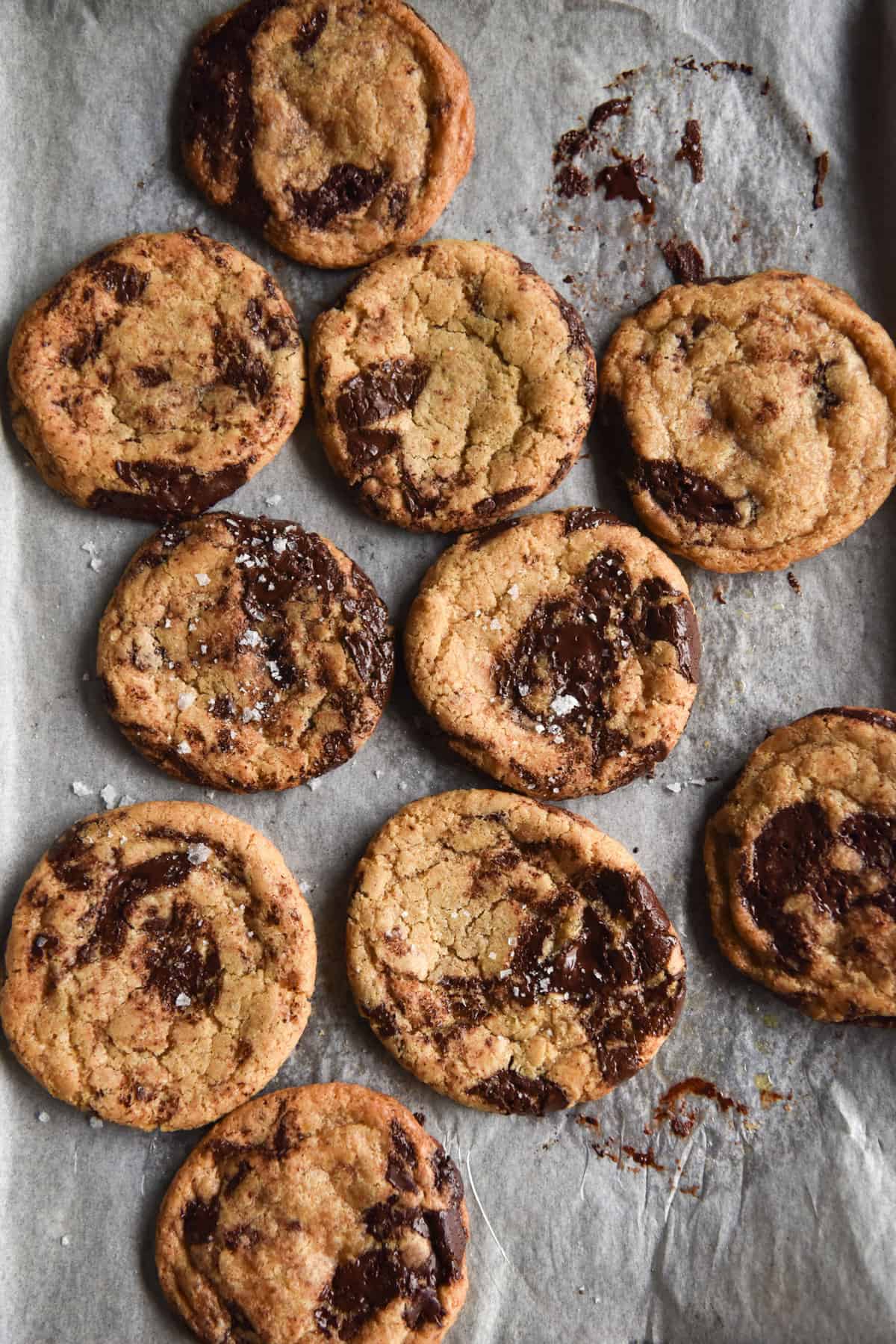 An aerial view of a baking tray lined with baking paper and topped with gluten free choc chip cookies.