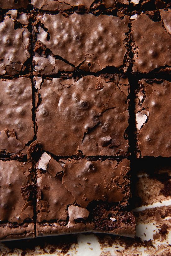 An aerial close up view of a slab of gluten free brownies slice on a sheet of baking paper