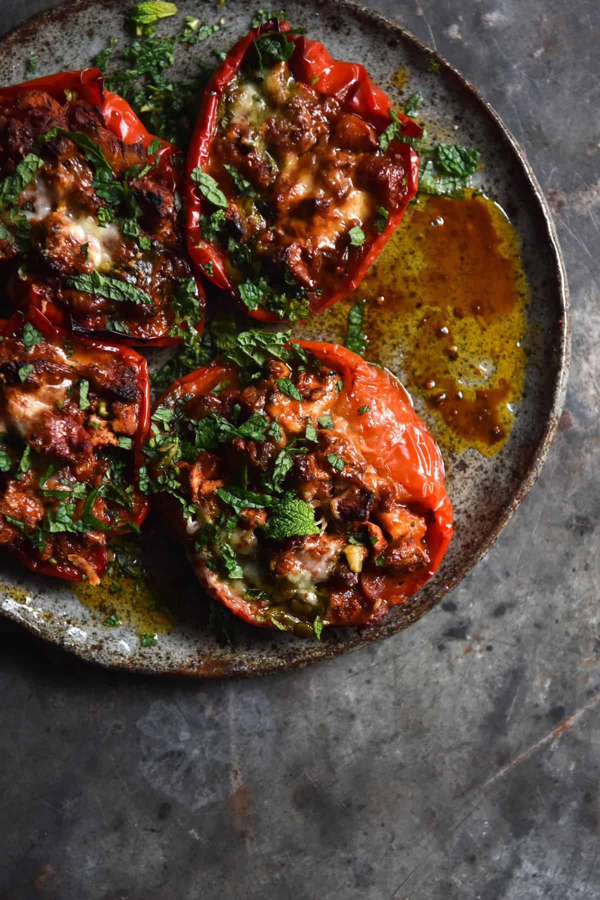 An aerial image of vegetarian mince stuffed capsicums on a dark blue ceramic plate atop a dark blue steel backdrop. 