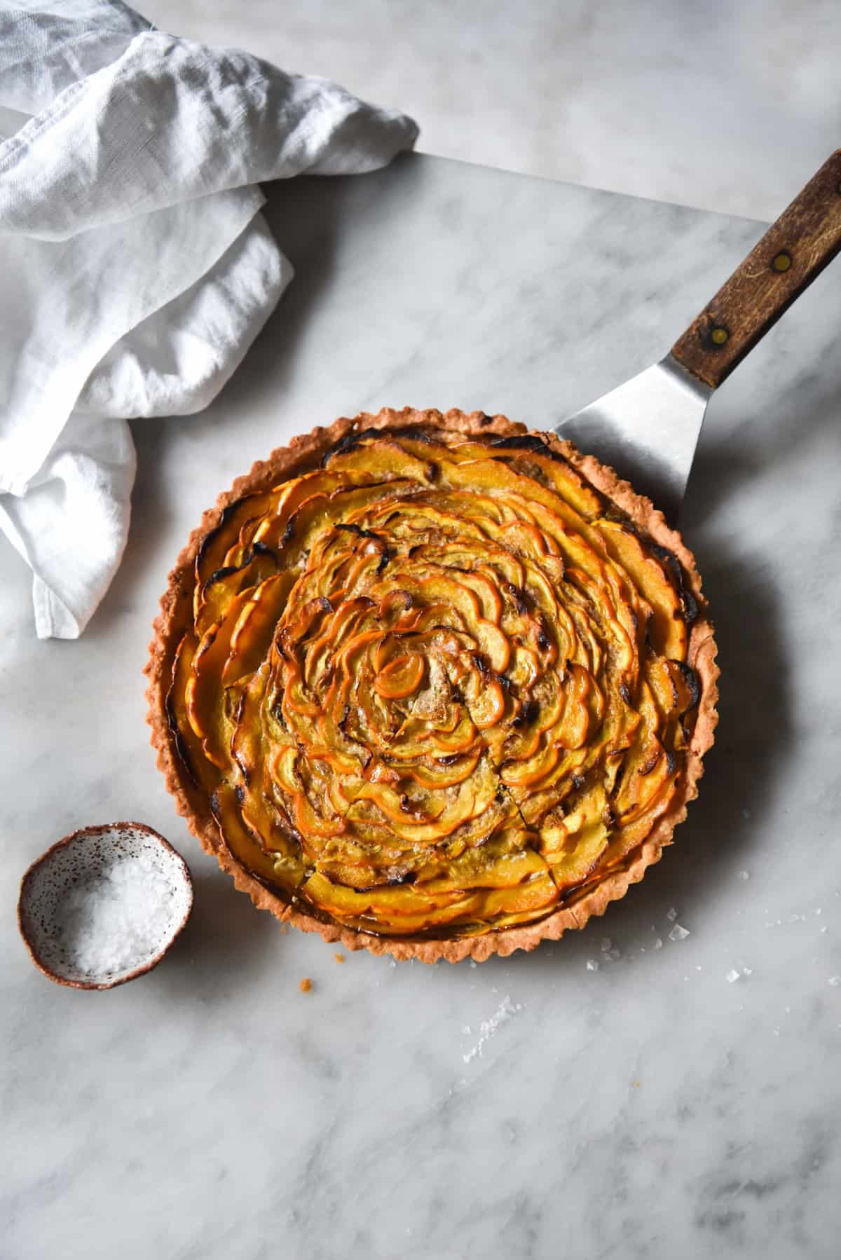 An aerial image of a gluten free savoury pumpkin tart on a white marble table