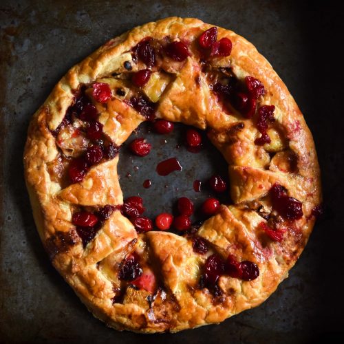 An aerial image of a gluten free brie cranberry wreath on a dark steel backdrop