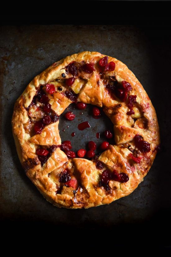 An aerial image of a gluten free brie cranberry wreath on a dark steel backdrop