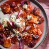 Blood orange, burrata, pine-nut salad with Christmas dressing sits atop a white ceramic plate on a pink linen backdrop