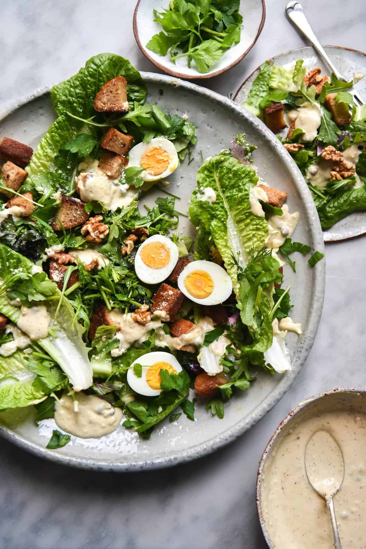 Vegetarian, Gluten Free and FODMAP Friendly Caesar Salad on a white plate atop a white marble table.