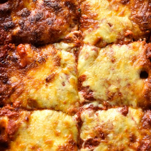 An aerial close up image of a tray of gluten free pasta bake with a cheesy, golden brown topping