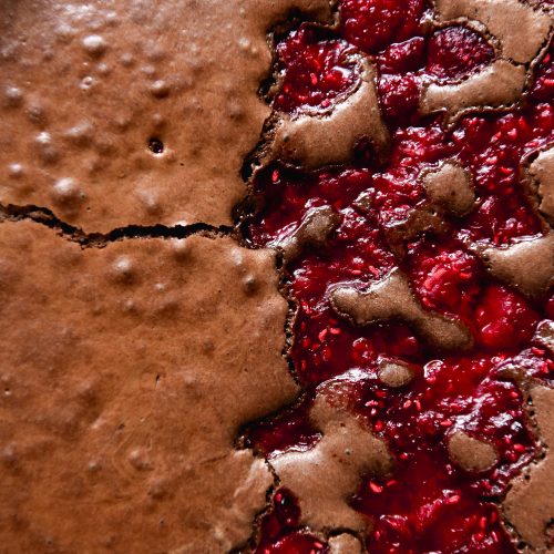 An aerial macro shot of a gluten free brownie that is half plain and half topped with raspberries