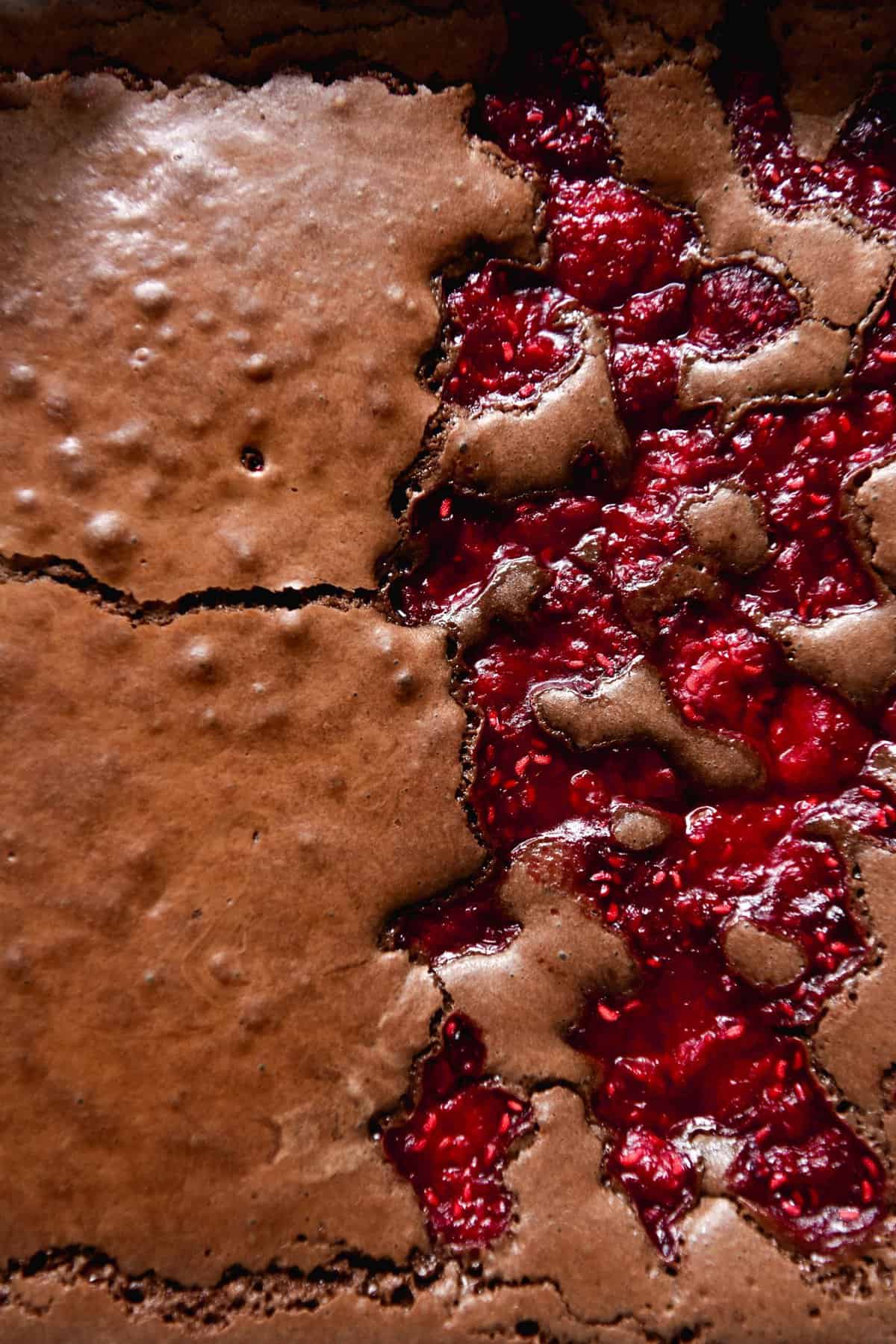 An aerial macro shot of a gluten free brownie that is half plain and half topped with raspberries