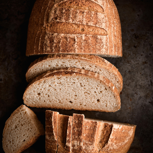 A moody aerial photo of a loaf of gluten free sourdough bread that has been sliced.