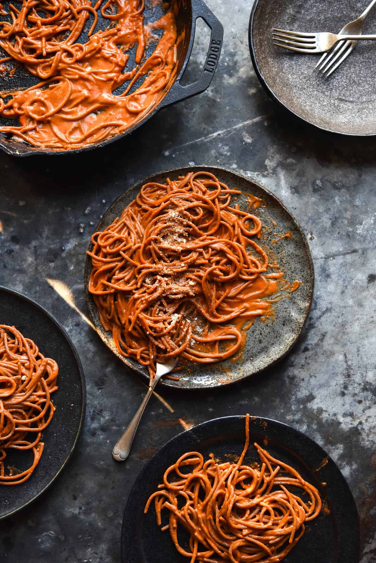 FODMAP friendly Pasta Alla Vodka on dark grey ceramic plates, casually arranged atop a mottled steel backdrop