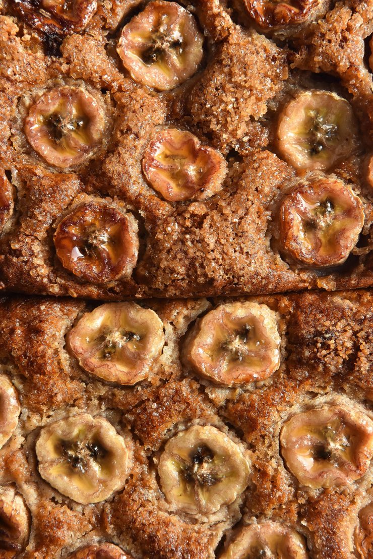 A close up of two loaves of gluten free sourdough banana bread topped with banana coins and finishing sugar