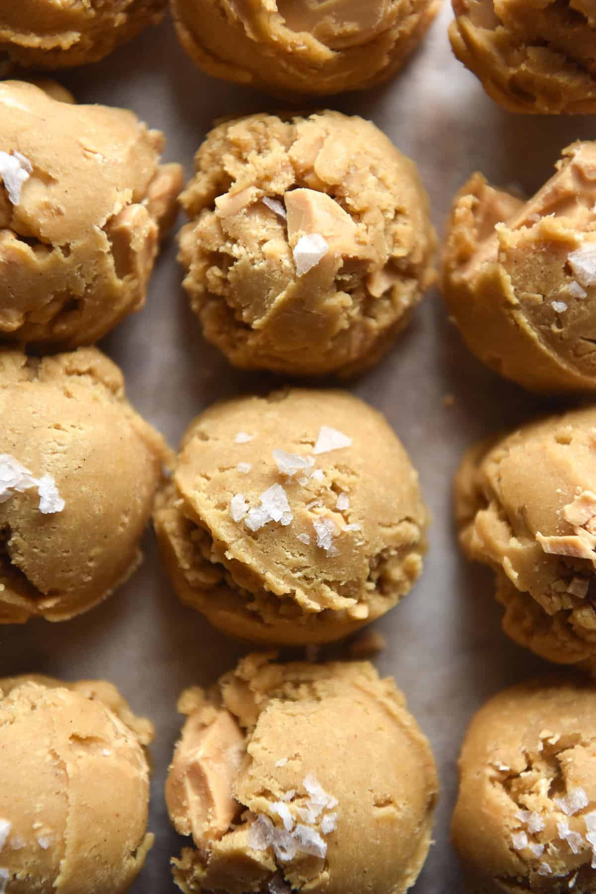 An aerial view of scoops of gluten free choc chip cookies with white chocolate and sea salt flakes.