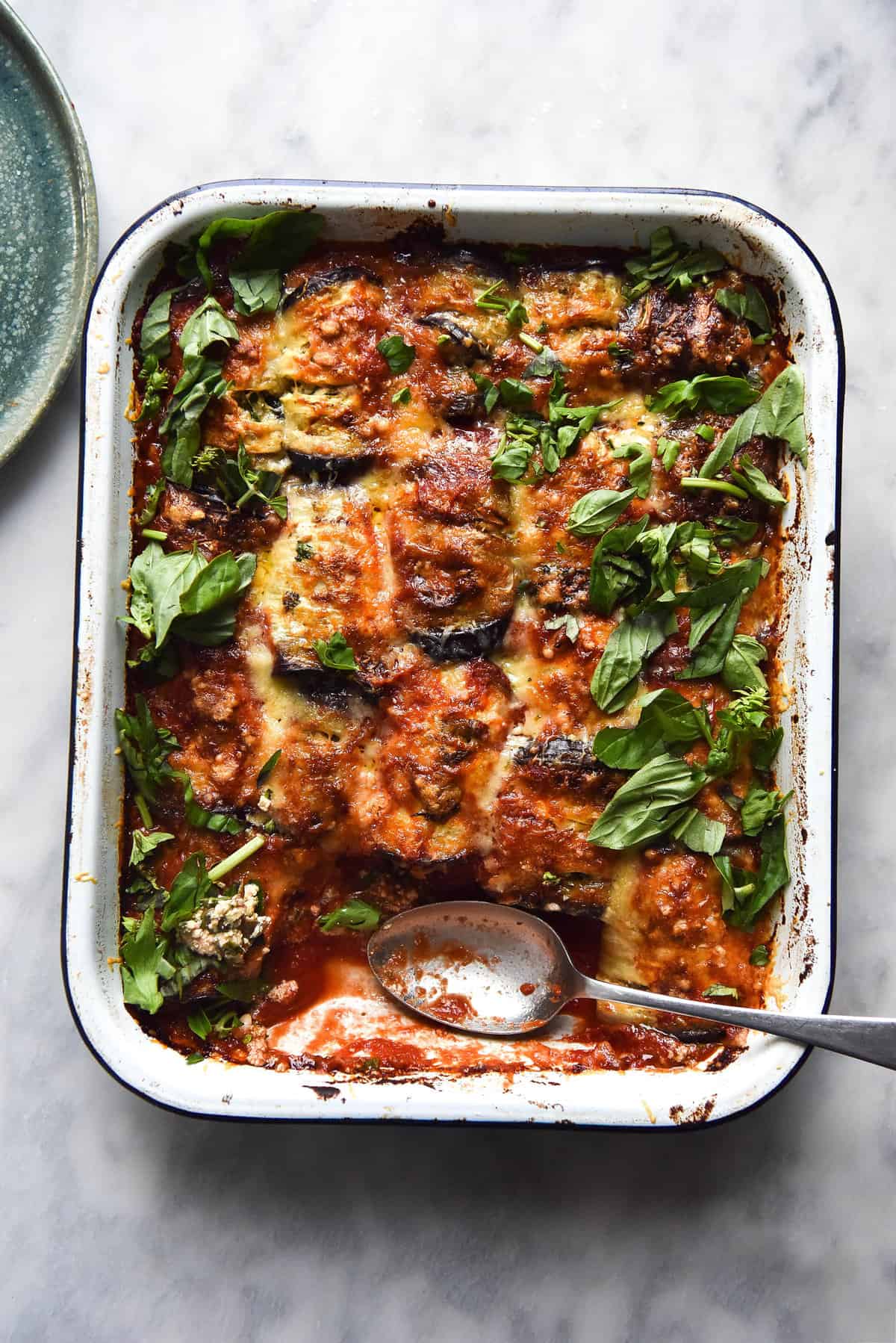 Cheesy vegan sausage involtini topped with herbs and served on a white marble backdrop