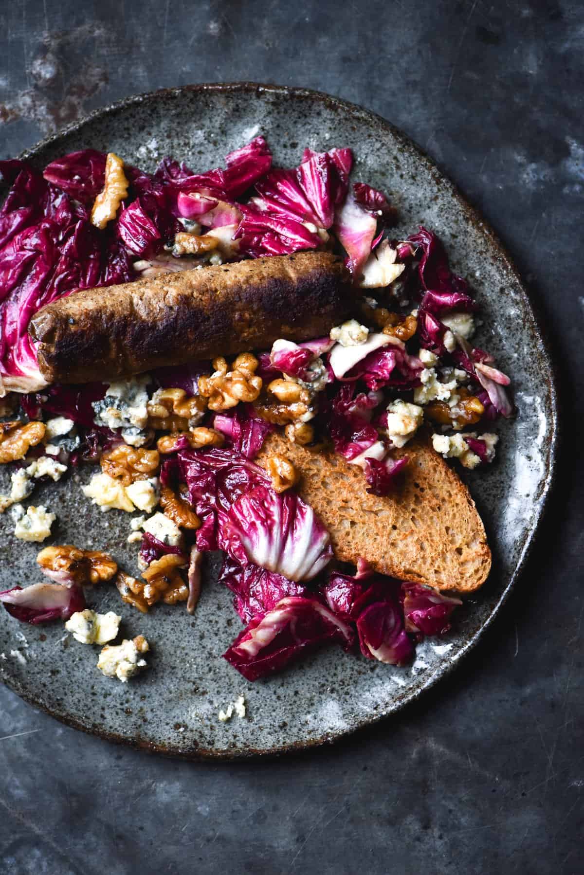 Radicchio salad with blue cheese, honey cinnamon walnuts and a sherry vinaigrette with a slice of toast on a blue backdrop