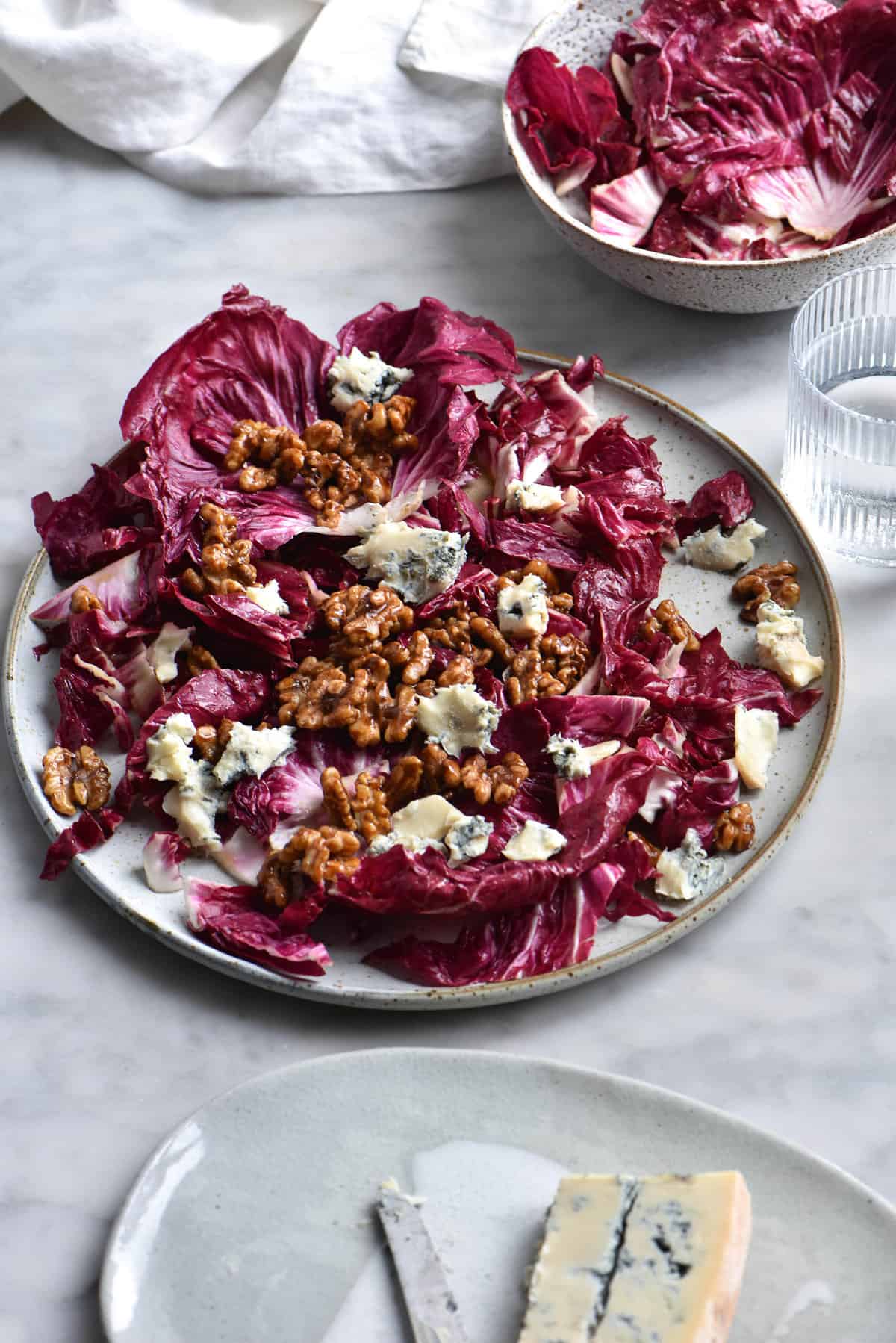 Radicchio salad with blue cheese. honey cinnamon walnuts and a sherry vinaigrette on a white marble backdrop