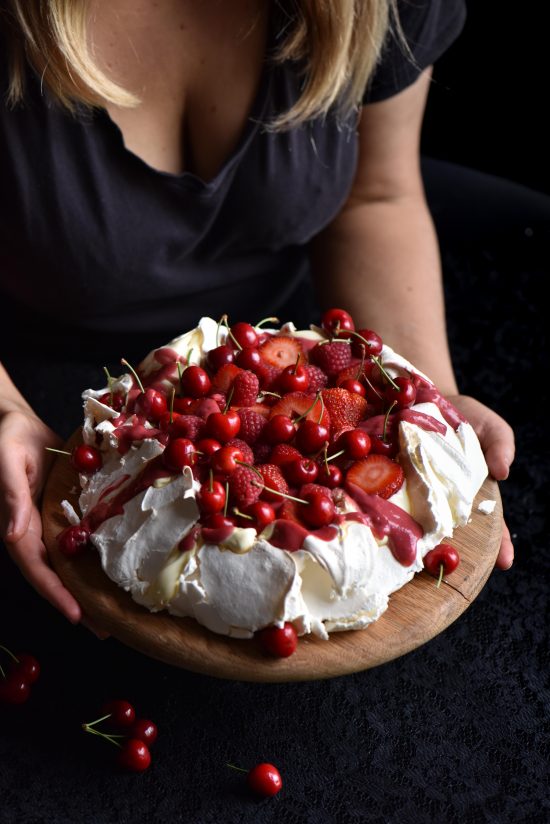 Pavlova with raspberry curd and topped with lots of red berries
