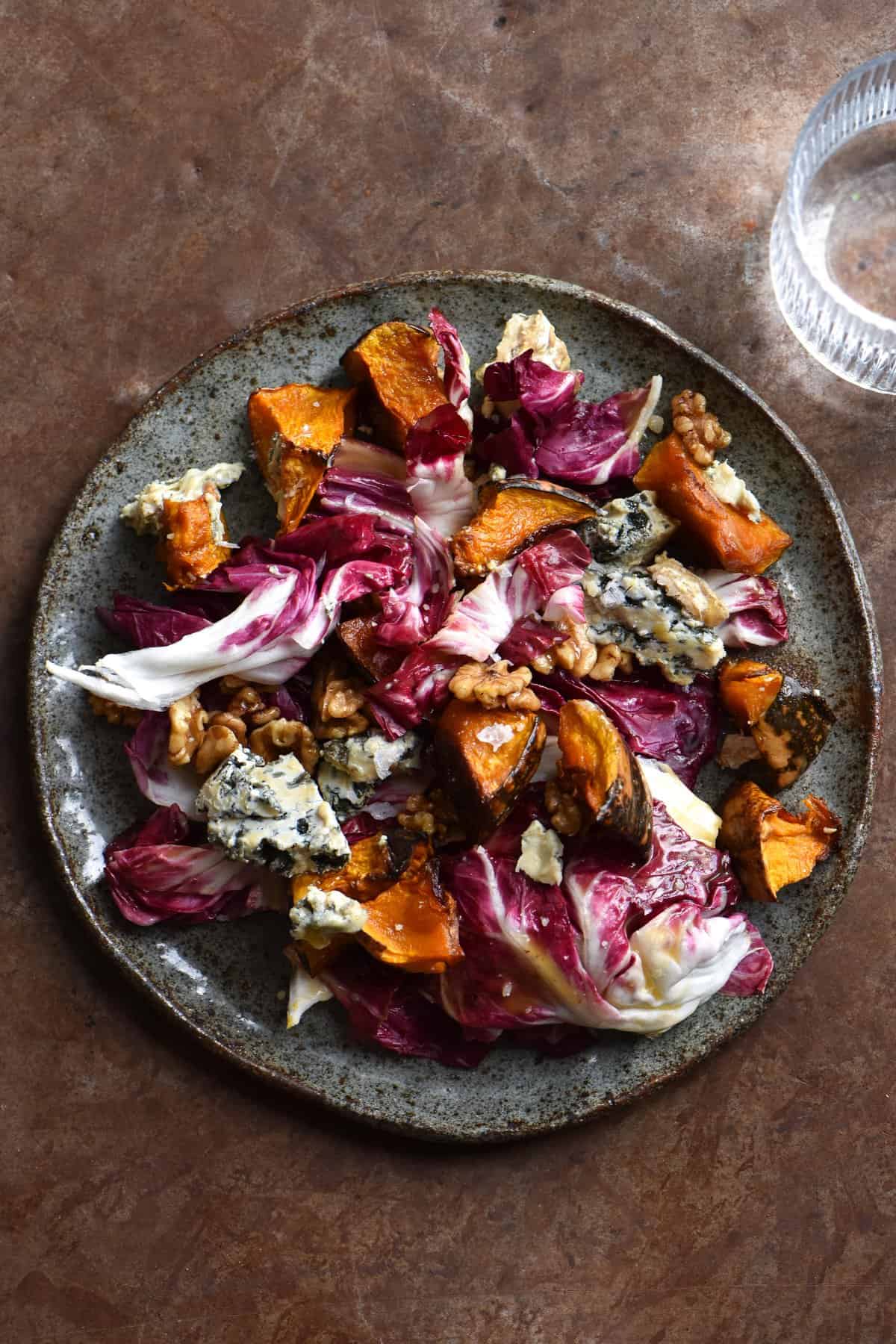 A radicchio, honeyed walnut, blue cheesed and roasted pumpkin salad against a rusty metallic backdrop