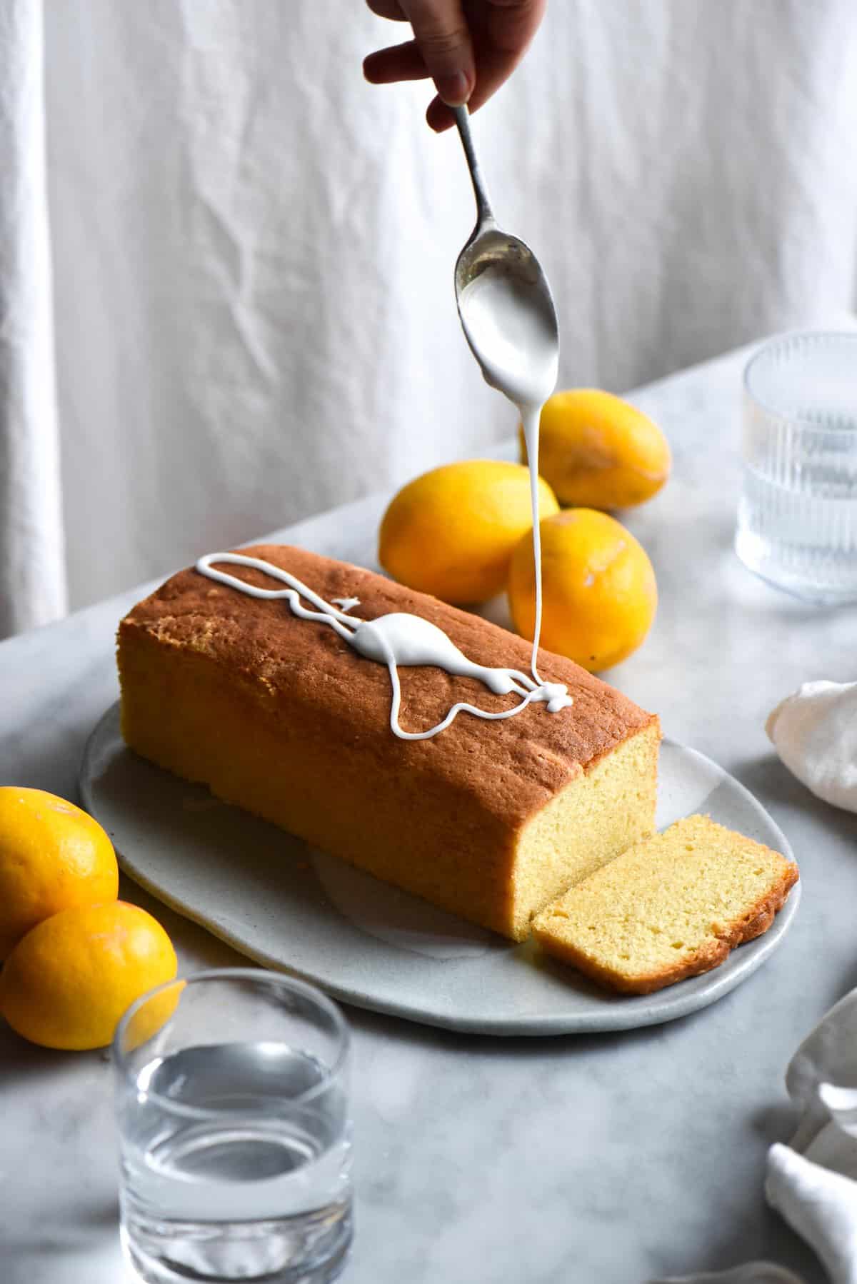 Gluten free lemon drizzle cake with lemon icing being drizzled over the top