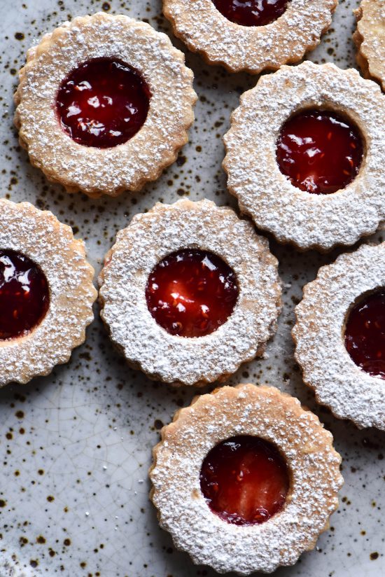Gluten free linzer cookies on a white ceramic speckled plate
