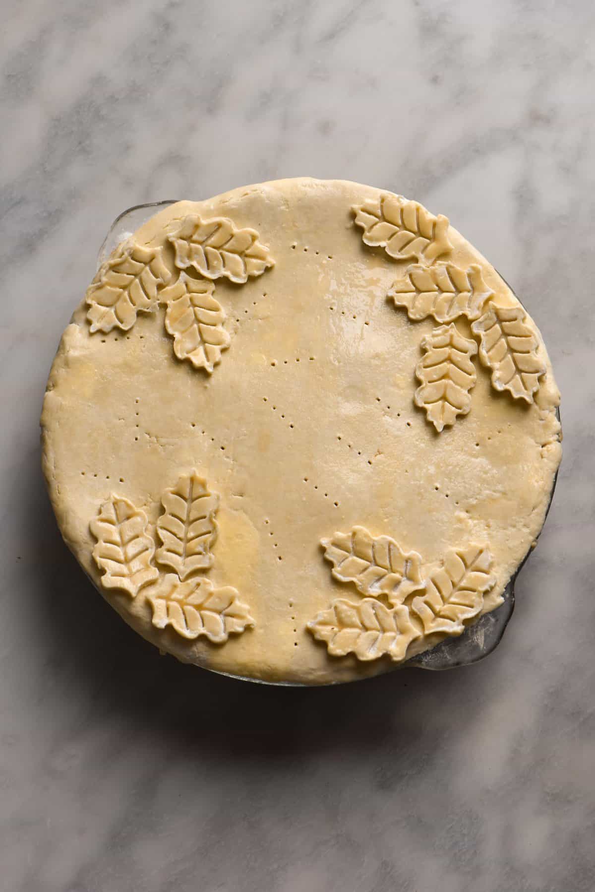 A gluten free greens pie topped with ornamental pastry leaves before baking