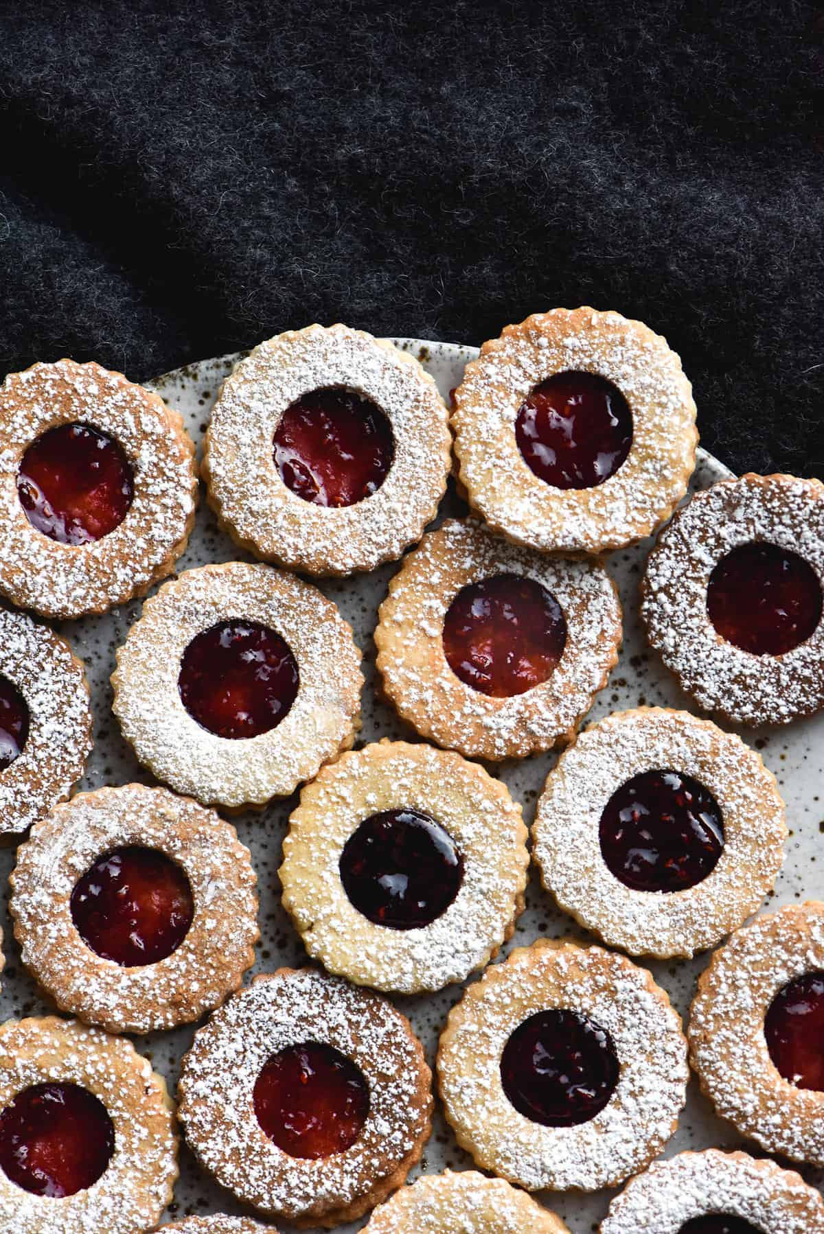 Gluten free linzer cookies against a fluffy dark grey jumper