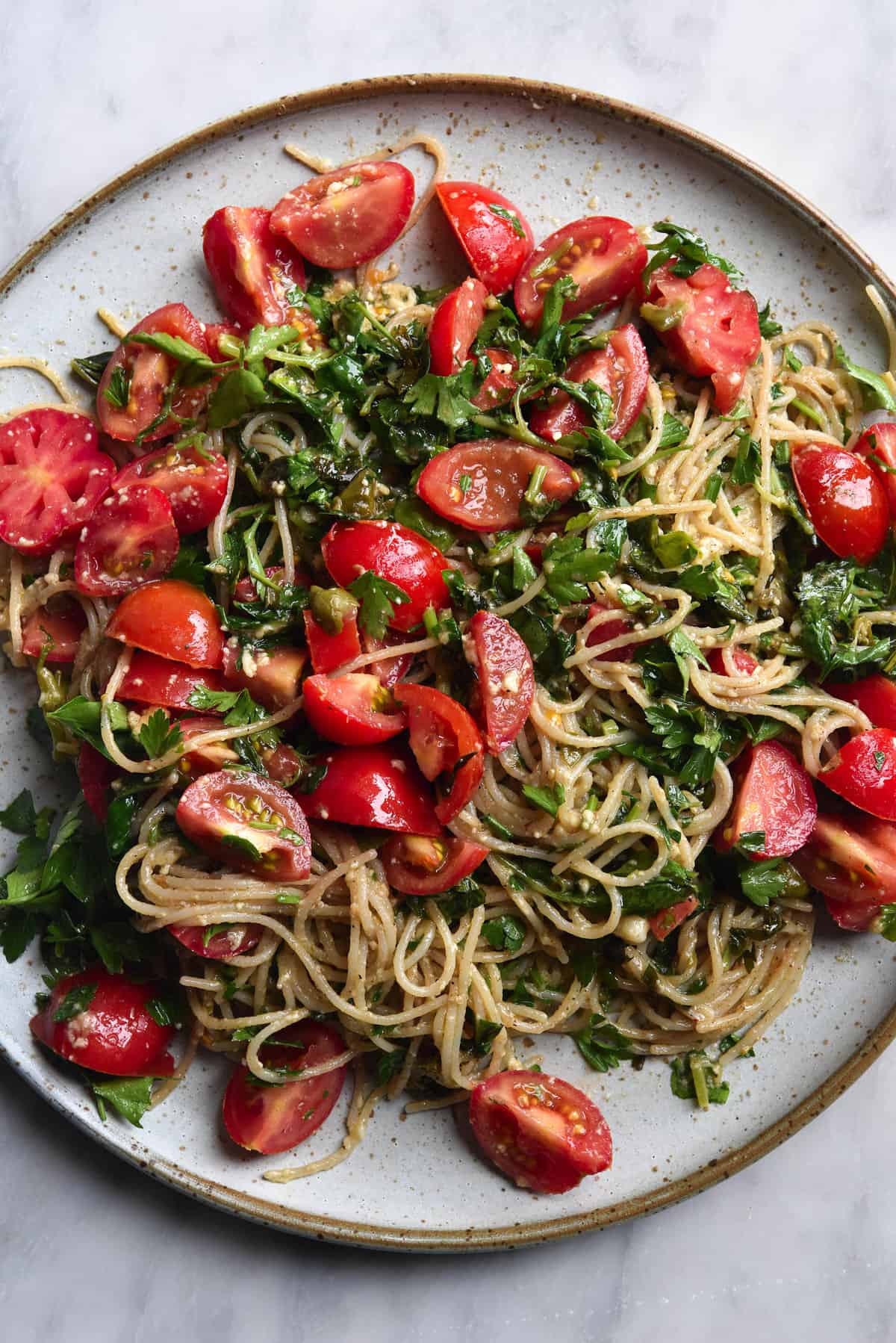 A close up of gluten free spaghetti with a brown butter, chilli, lemon and herb sauce and fresh summer tomatoes