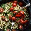 Gluten free pasta with a brown butter, herb, chilli and lemon dressing, topped with fresh summer tomatoes. Served in a skillet set against an olive green linen tablecloth