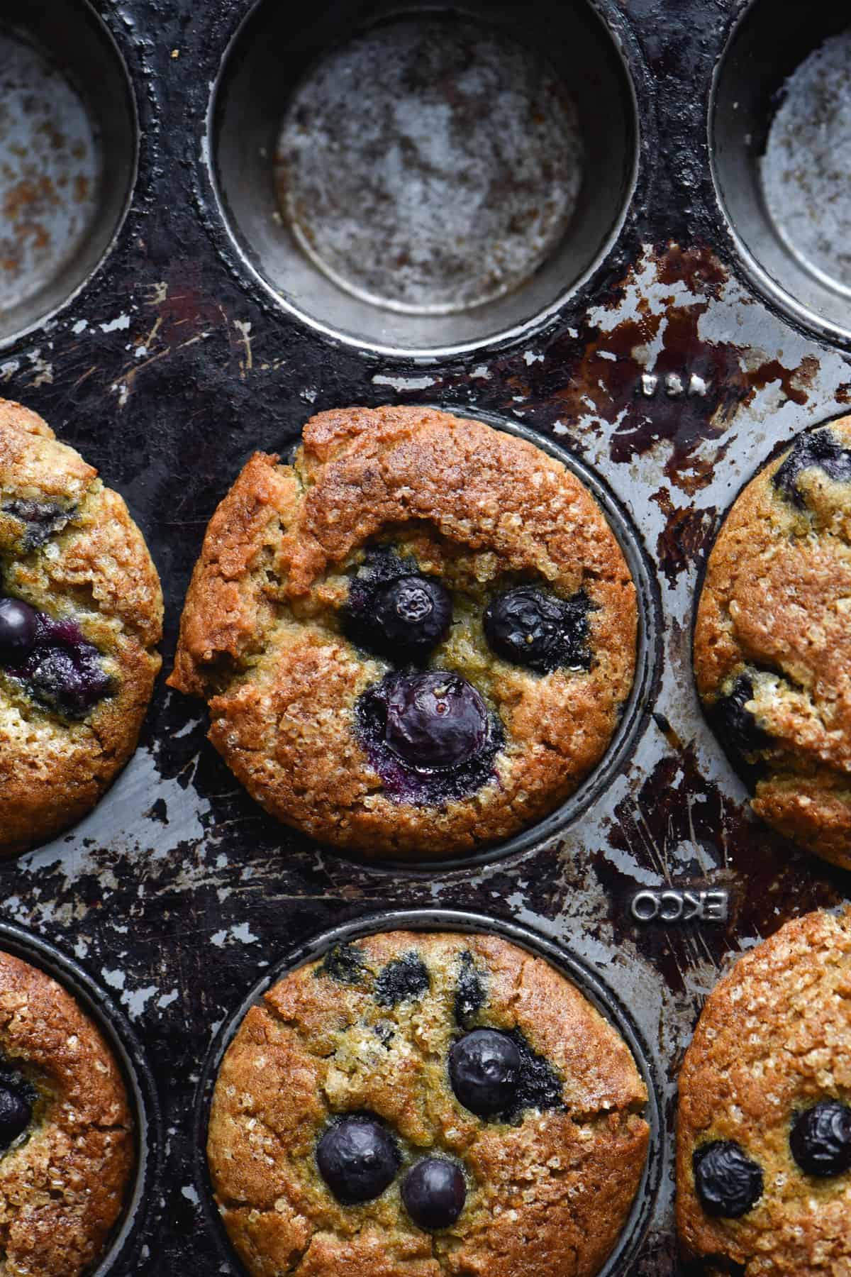 A half filled tray of vegan gluten-free blueberry muffins topped with finishing sugar