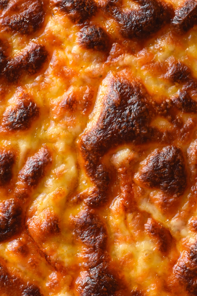 A close up of a cheesy margherita pizza with bubbly browned mozzarella