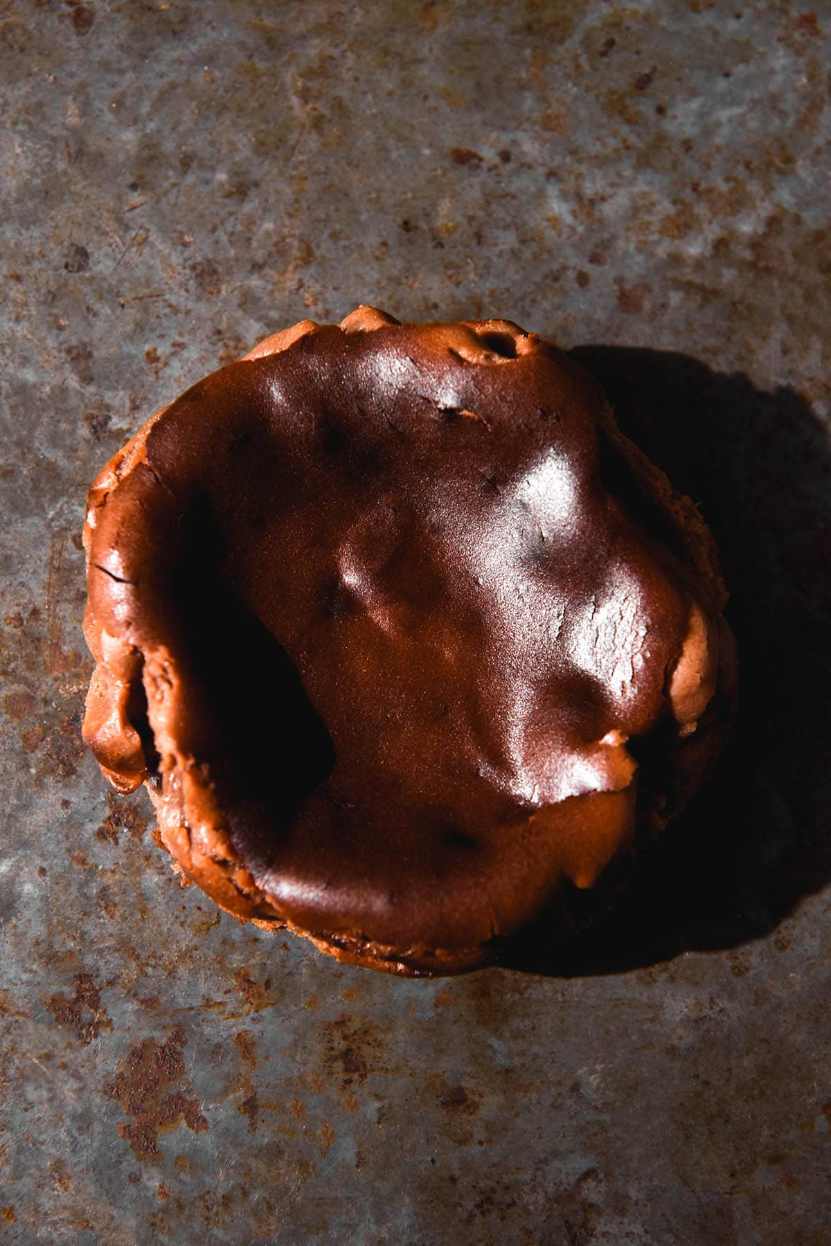 A moody aerial image of a mini chocolate cheesecake on a dark steel backdrop