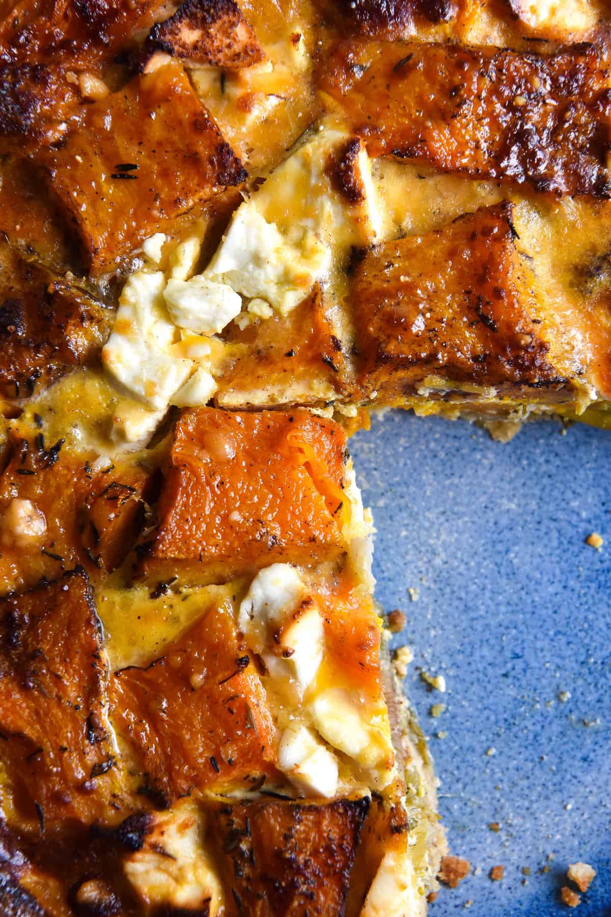 A close up aerial image of a gluten free pumpkin tart on a bright blue ceramic plate. 