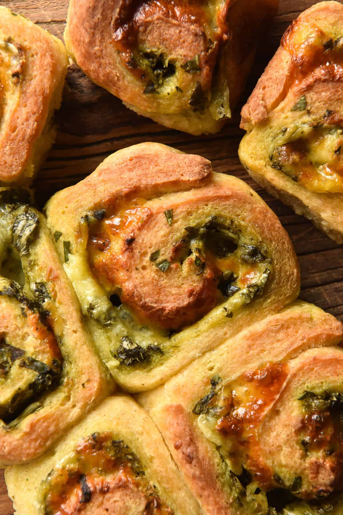 An aerial close up image of gluten free pesto scrolls on a dark backdrop.