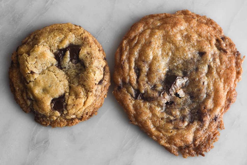 An instructional image to demonstrate the impact of different brands of white rice flour. Two cookies sit atop a marble table: one has spread considerably in the oven and has very lace-like edges. The other is a lot thicker, rounder and has held it's shape nicely.