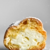 A side on macro view of a gluten free cream puff that has been sliced in half, exposing the whipped cream innards