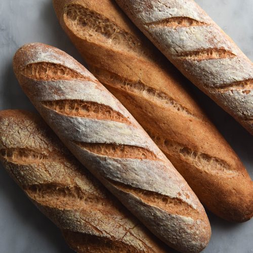 A close up aerial view of four gluten free baguettes sitting snug on a white marble table