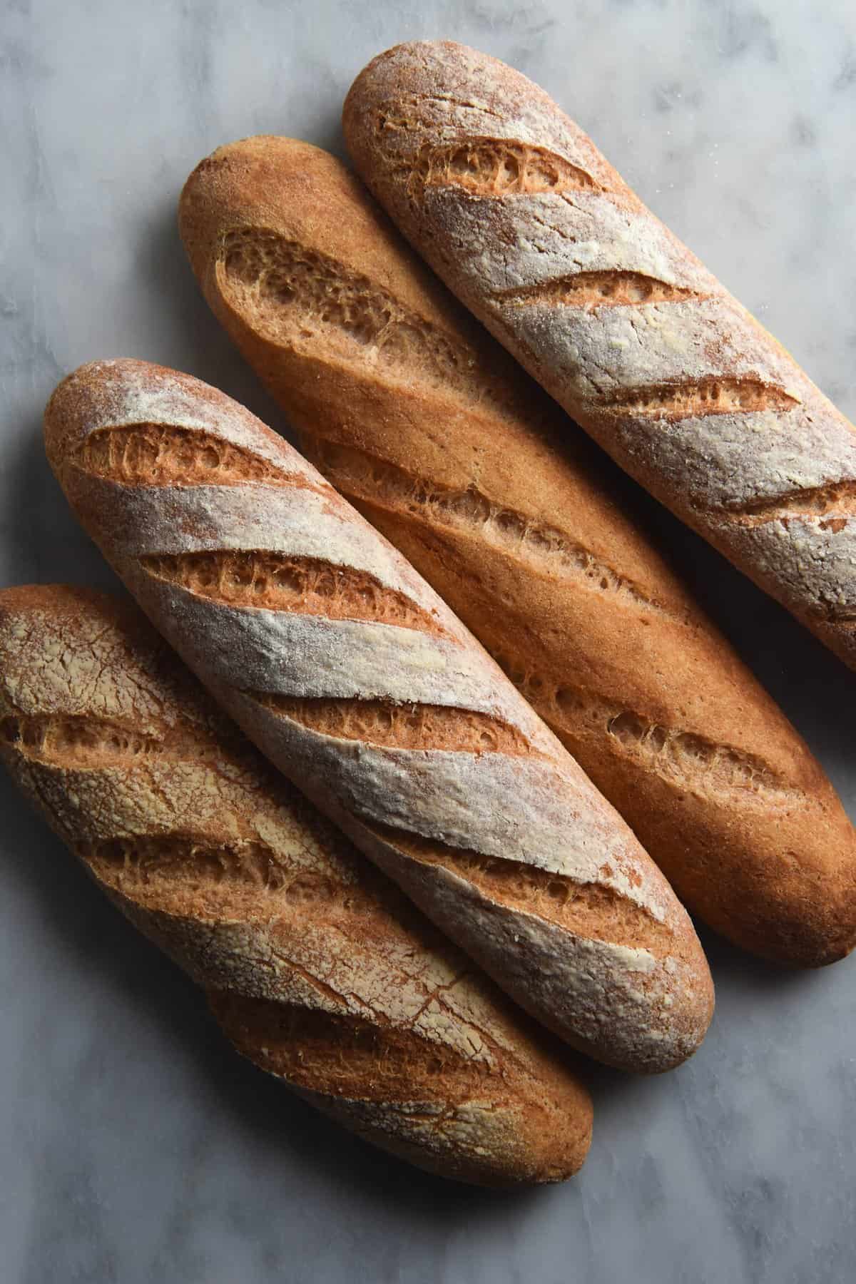 A close up aerial view of four gluten free baguettes sitting snug on a white marble table