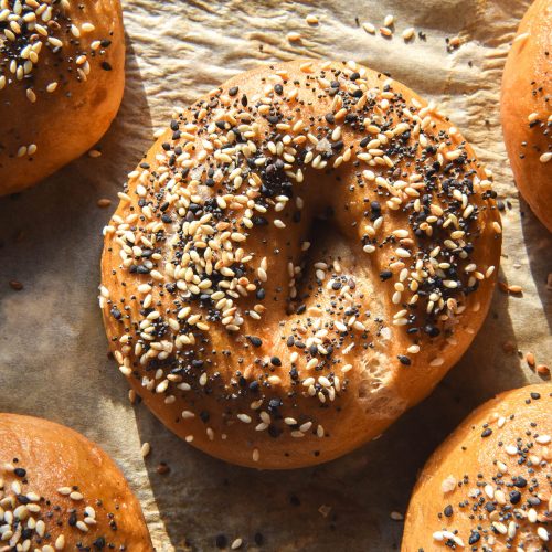 An aerial view of a baking tray of gluten free bagels topped with FODMAP friendly everything bagel seasoning