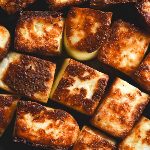 A close up macro photo of golden brown fried cubes of paneer