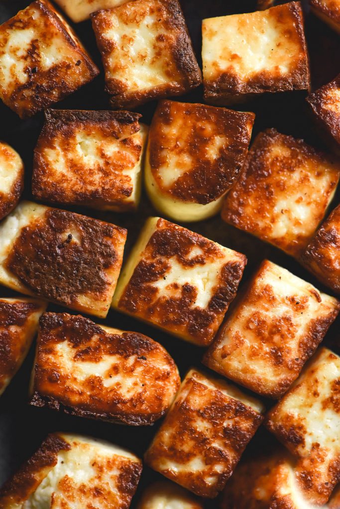 A close up macro photo of golden brown fried cubes of paneer