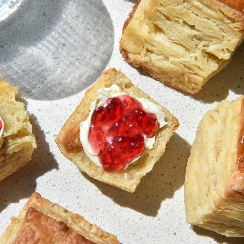 An aerial image of gluten free biscuits (American style) on a brightly lit white bench top.